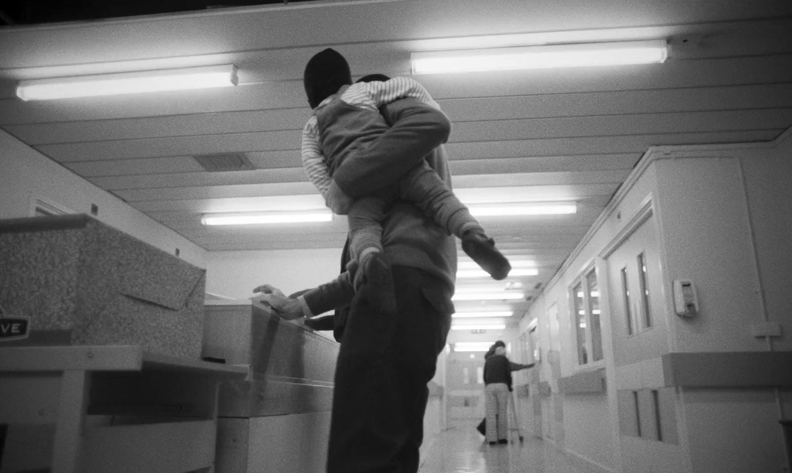 a black and white photo of a person walking down a hallway