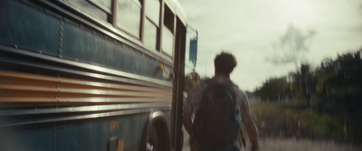 a man with a backpack is walking towards a bus