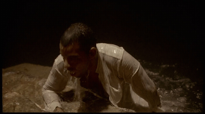 a man in white shirt laying on top of a rock