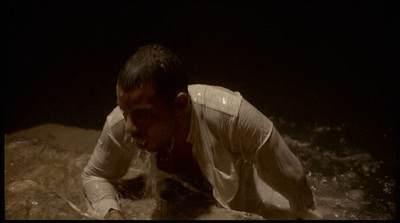 a man in white shirt laying on top of a rock