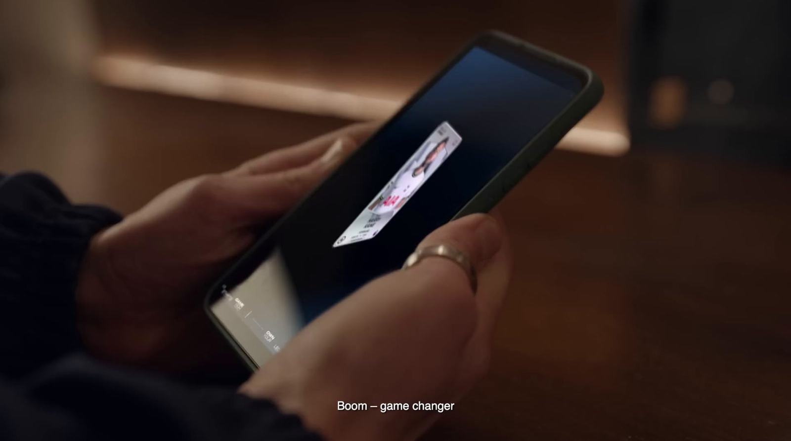 a person holding a cell phone on a wooden table