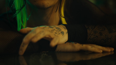 a man with green hair and tattoos on his arm