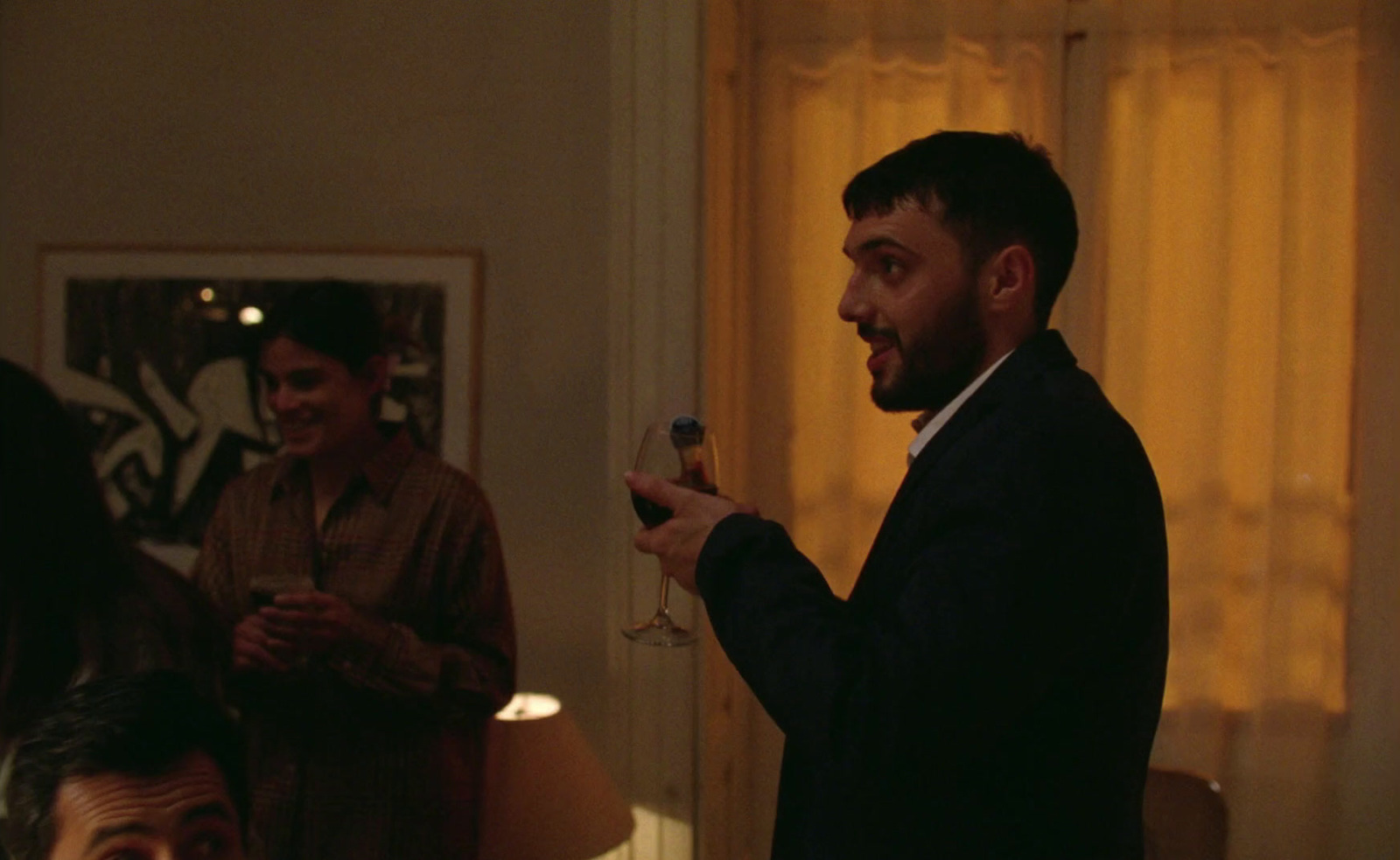 a man standing in a living room holding a wine glass