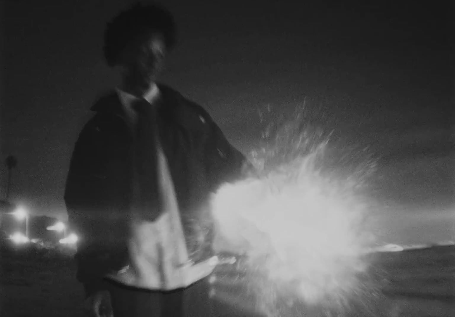 a black and white photo of a man holding a sparkler