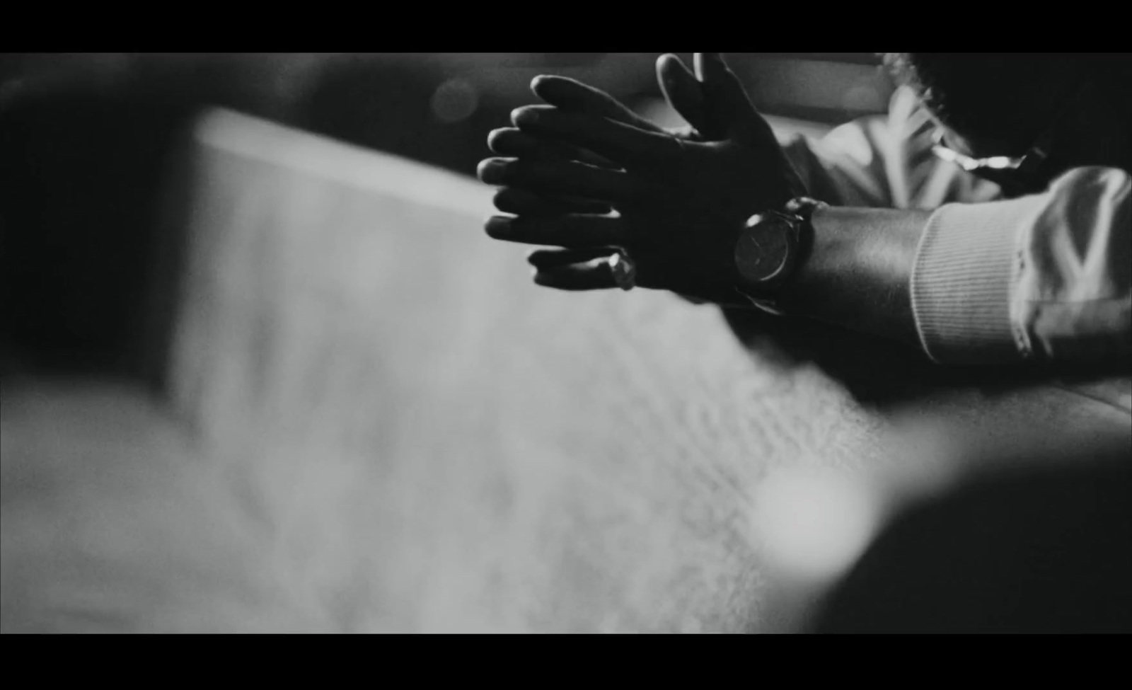 a black and white photo of a person's hands resting on a bench