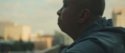 a man with a bald head looking out a window