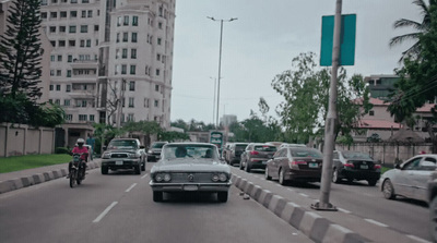 a group of cars driving down a street next to tall buildings