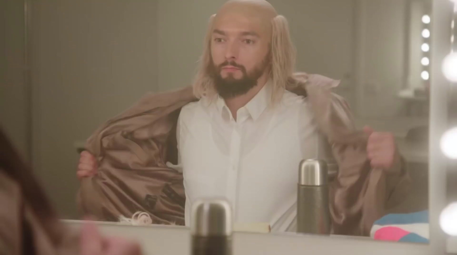 a man with long hair and a beard standing in front of a mirror