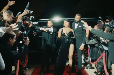 a group of people standing on a red carpet next to a car