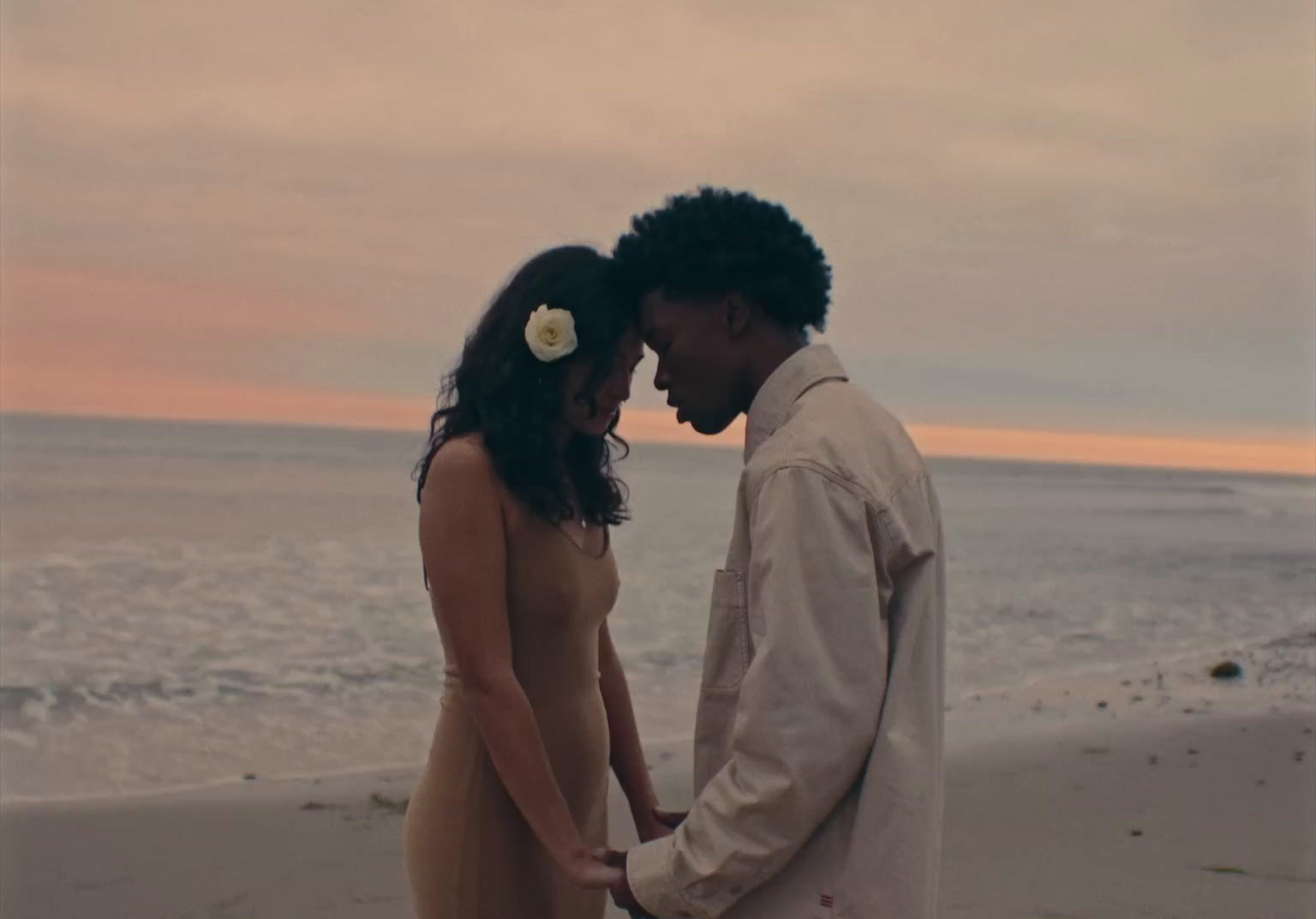 a man and woman standing on a beach next to the ocean