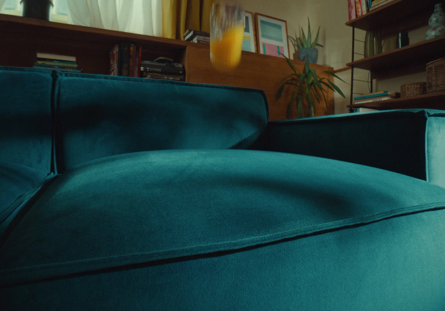 a blue couch in a living room next to a book shelf