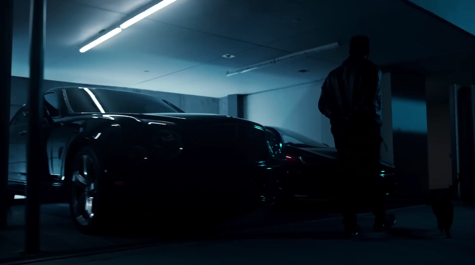 a man standing next to a car in a dark garage