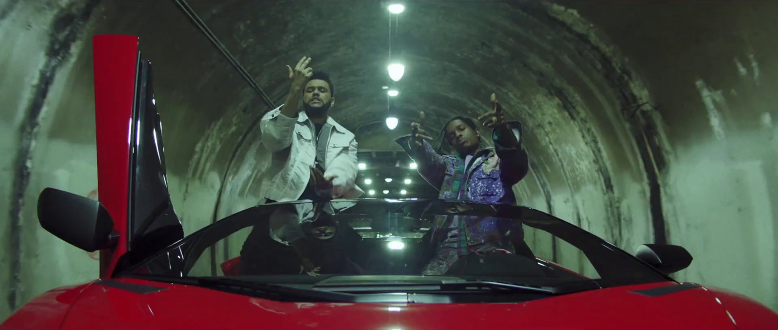 a group of people standing in a tunnel next to a red car