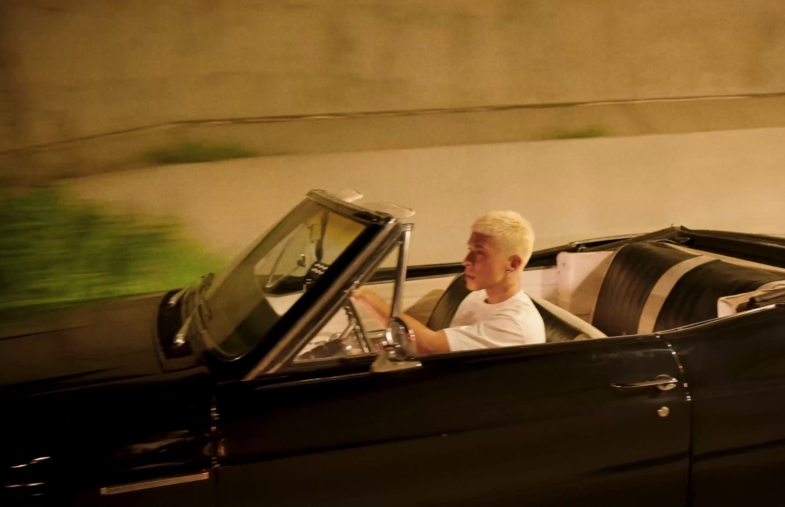 a man driving a black convertible car down a street