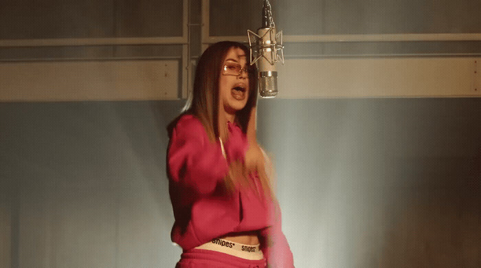 a woman in a pink top is singing into a microphone