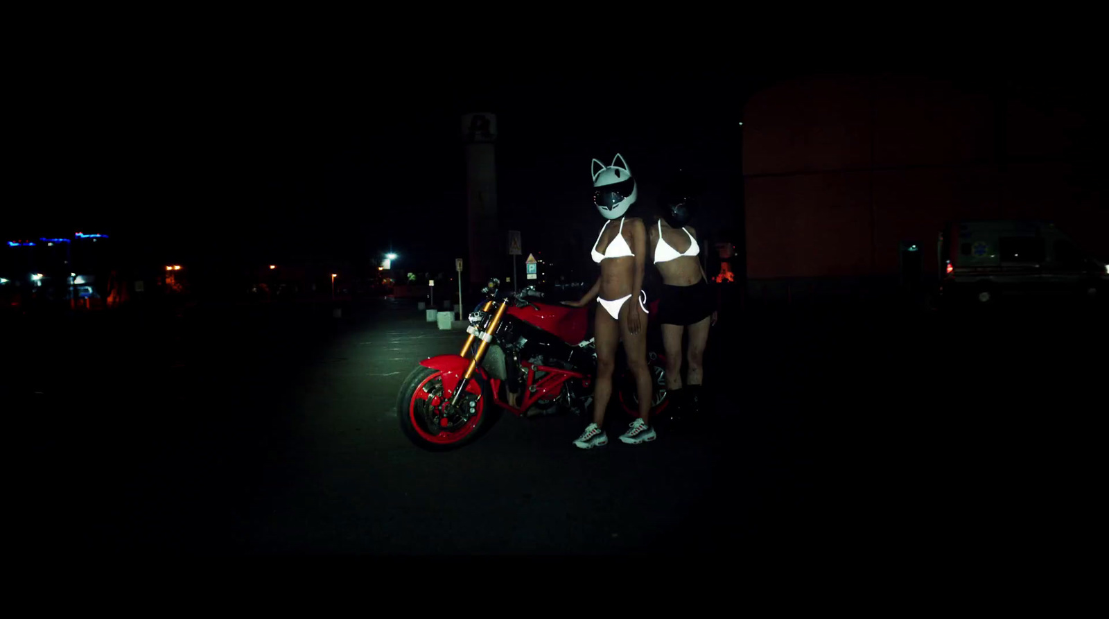 two women standing next to a motorcycle in the dark