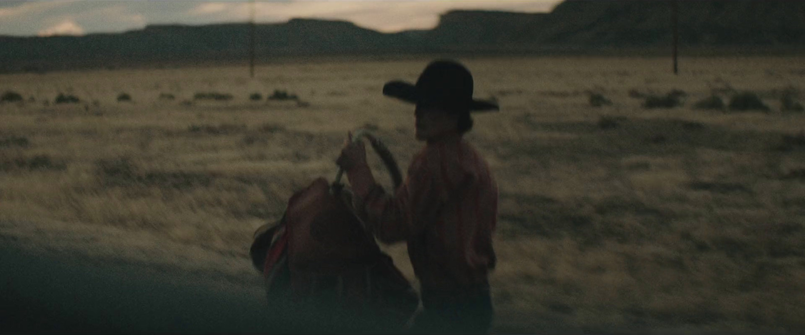 a man in a cowboy hat walking across a field