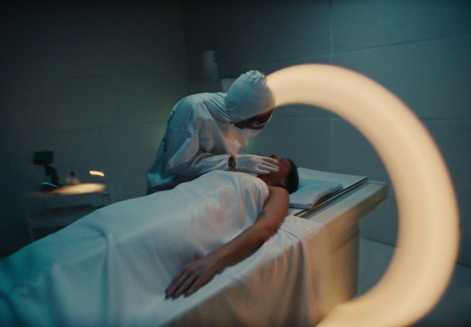 a person laying in a bed with a person wearing a surgical mask