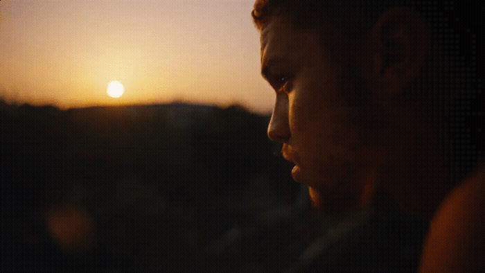 a man looking out a window at the sunset