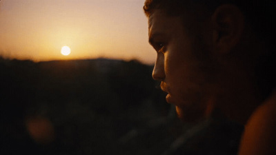 a man looking out a window at the sunset