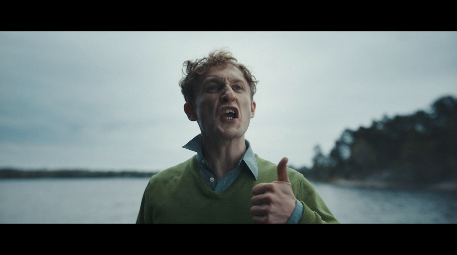 a man with a green shirt is giving a thumbs up