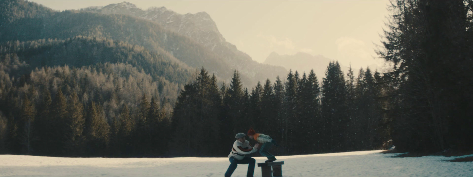 two people sitting on a bench in the snow