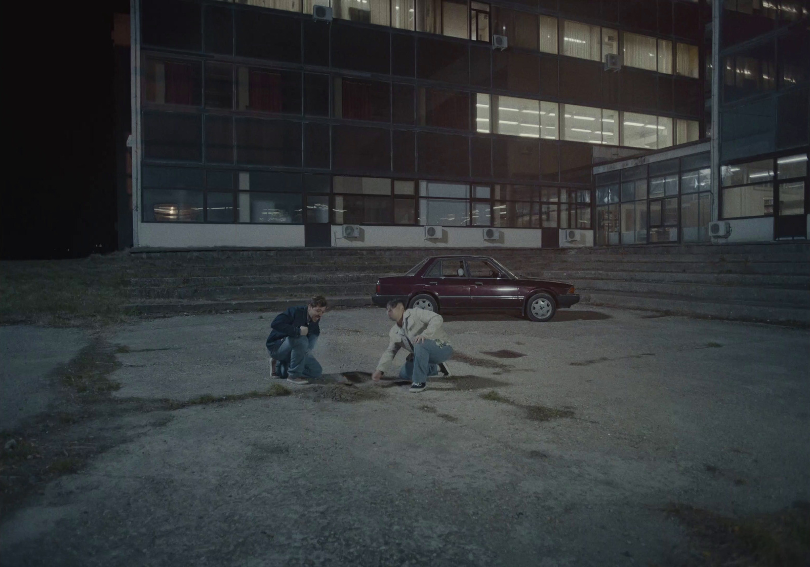 a couple of men standing next to a red car