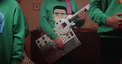 a group of people in green sweaters holding a white guitar