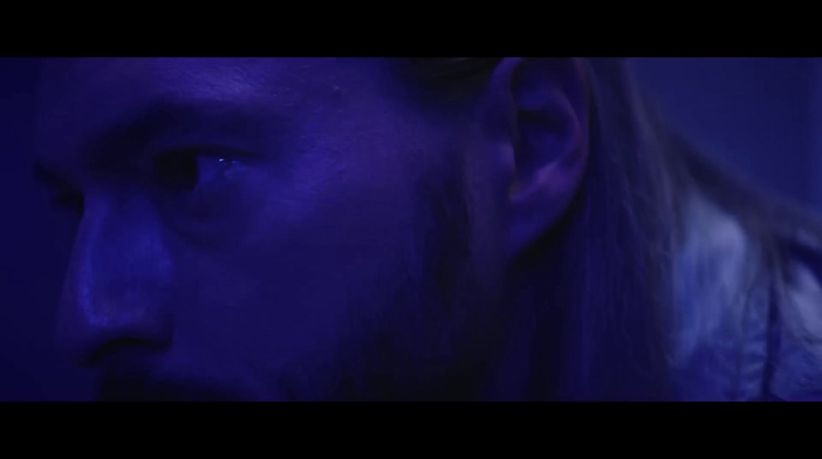 a man with long hair and a beard in a dark room