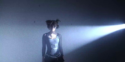 a woman standing in a dark room with a light shining on her