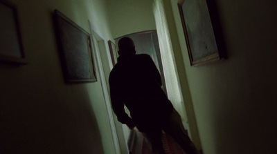 a man walking down a hallway in a dark room