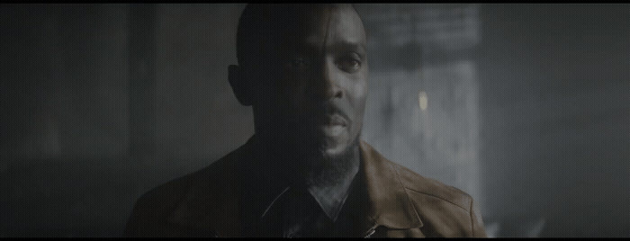 a man in a leather jacket standing in a dark room