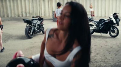 a woman in a white tank top standing next to a motorcycle