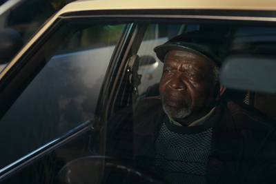 a man sitting in a car with a hat on