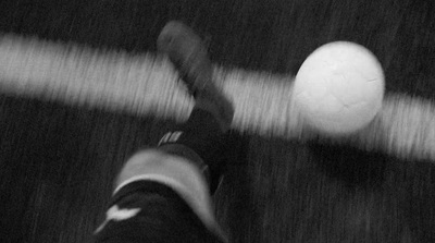 a black and white photo of a person kicking a soccer ball