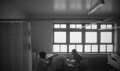 a black and white photo of three people in a hospital room