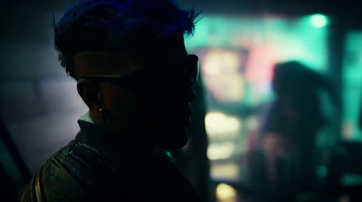 a man with blue hair and sunglasses in a dark room