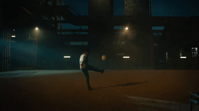 a man is kicking a soccer ball in the dark