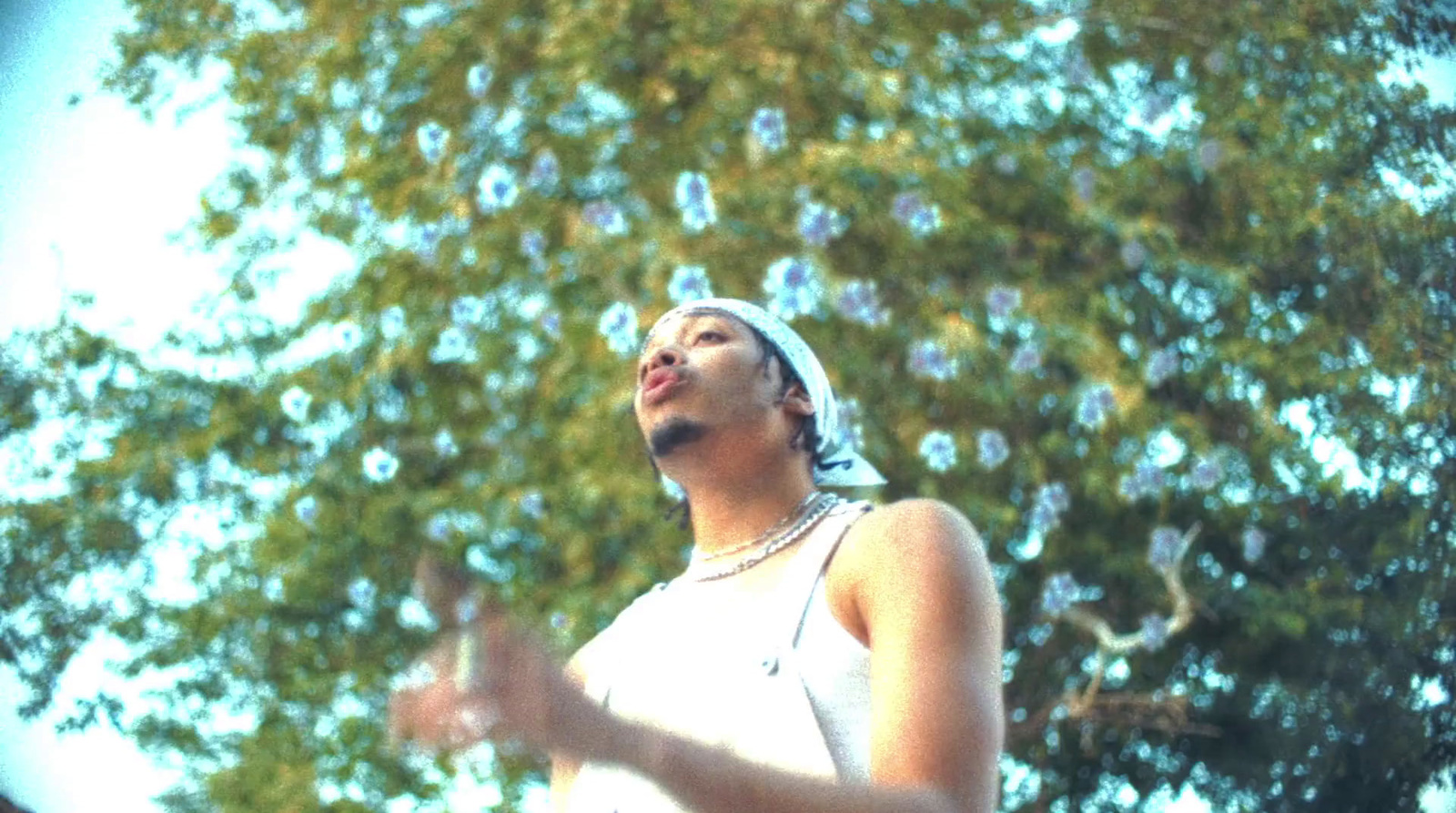 a woman standing in front of a tree blowing bubbles