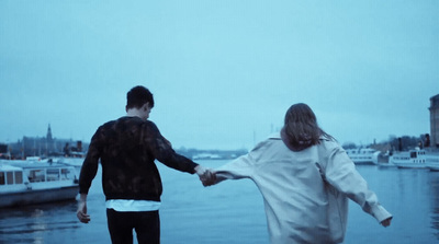 a man and a woman holding hands near a body of water