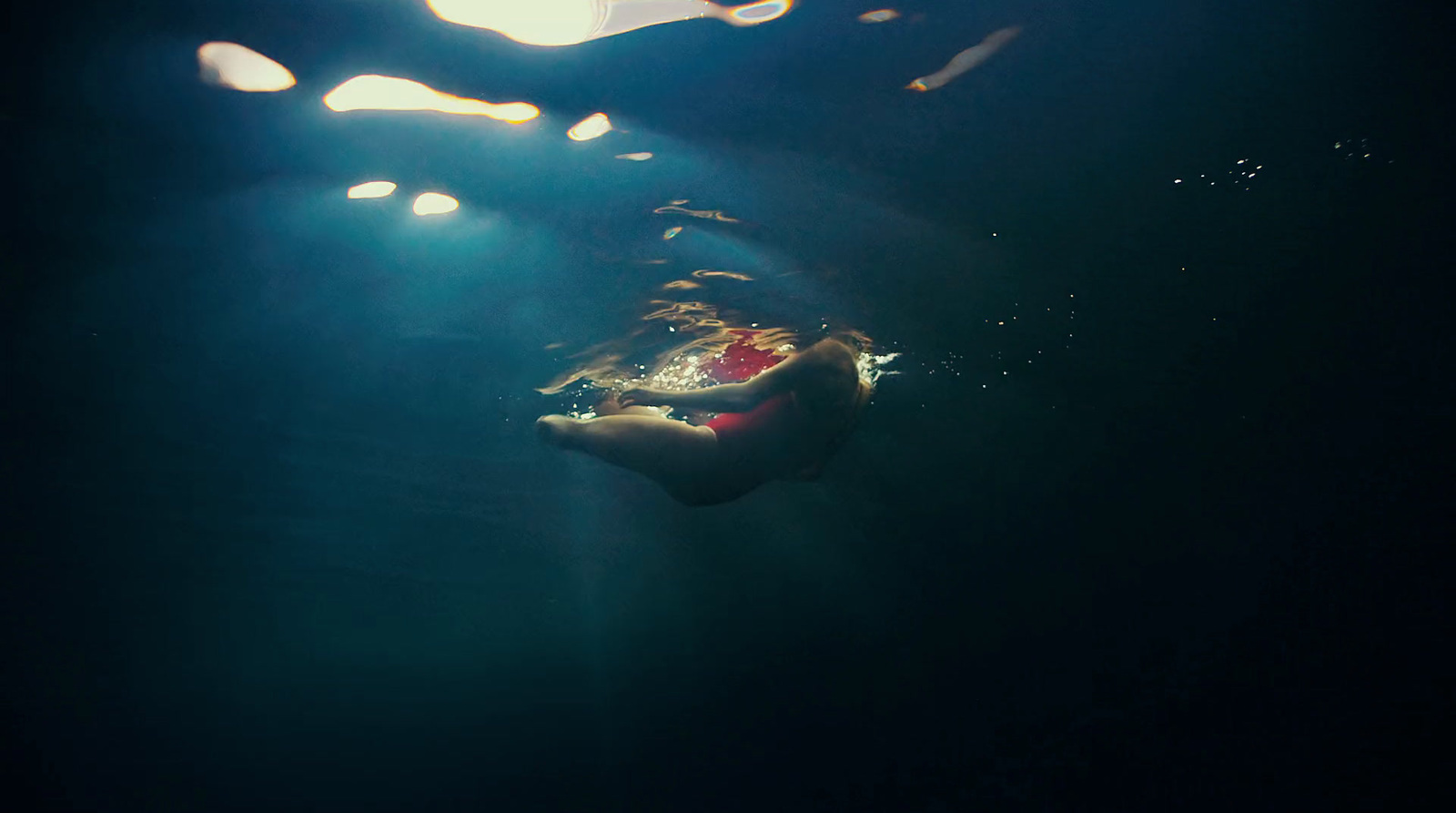 a person swimming in the water under a light