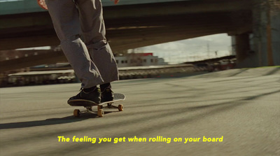 a man riding a skateboard down a street next to a bridge