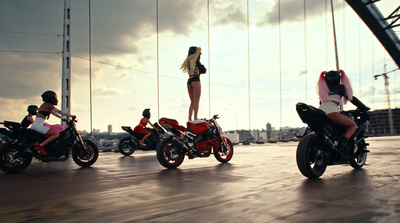 a woman standing on the back of a red motorcycle