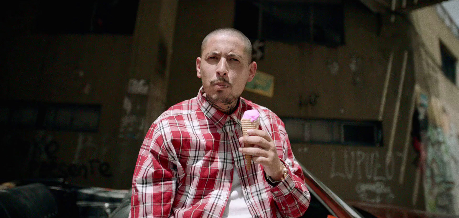 a man in a red and white checkered shirt holding an ice cream cone