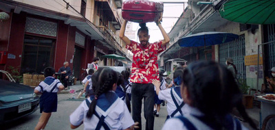 a man carrying a box on his head down a street