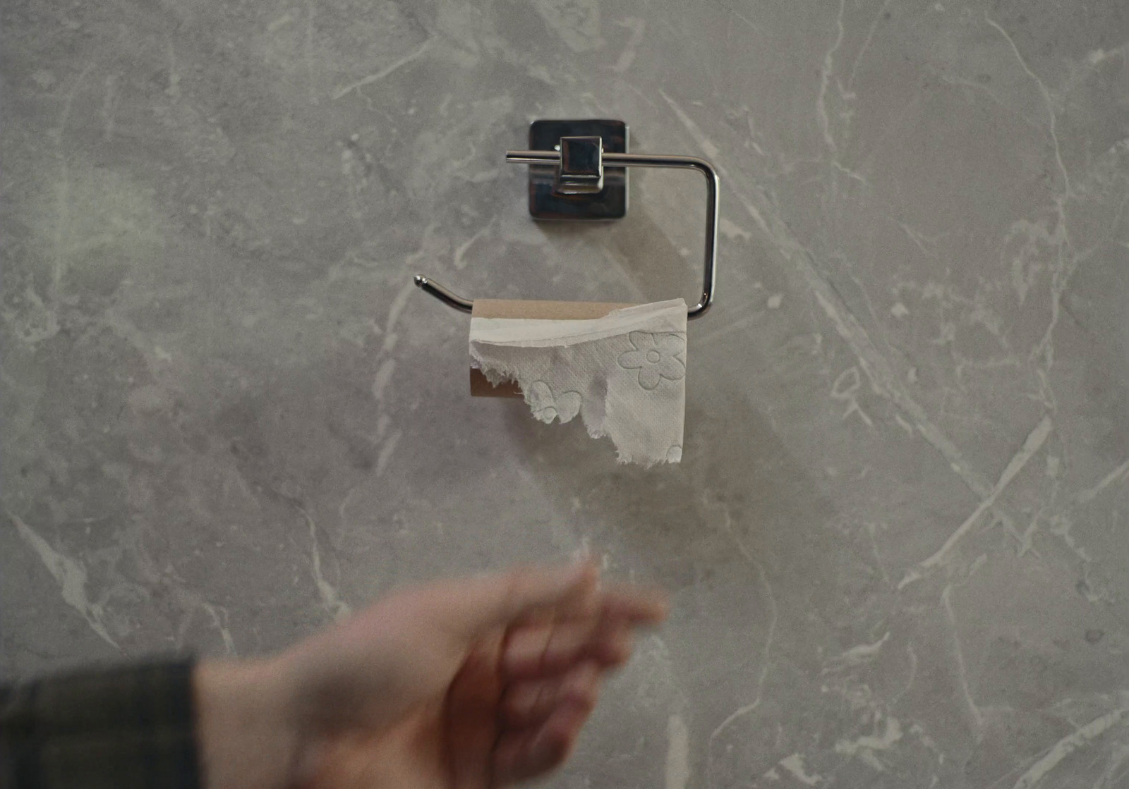 a hand holding a roll of toilet paper next to a roll of toilet paper