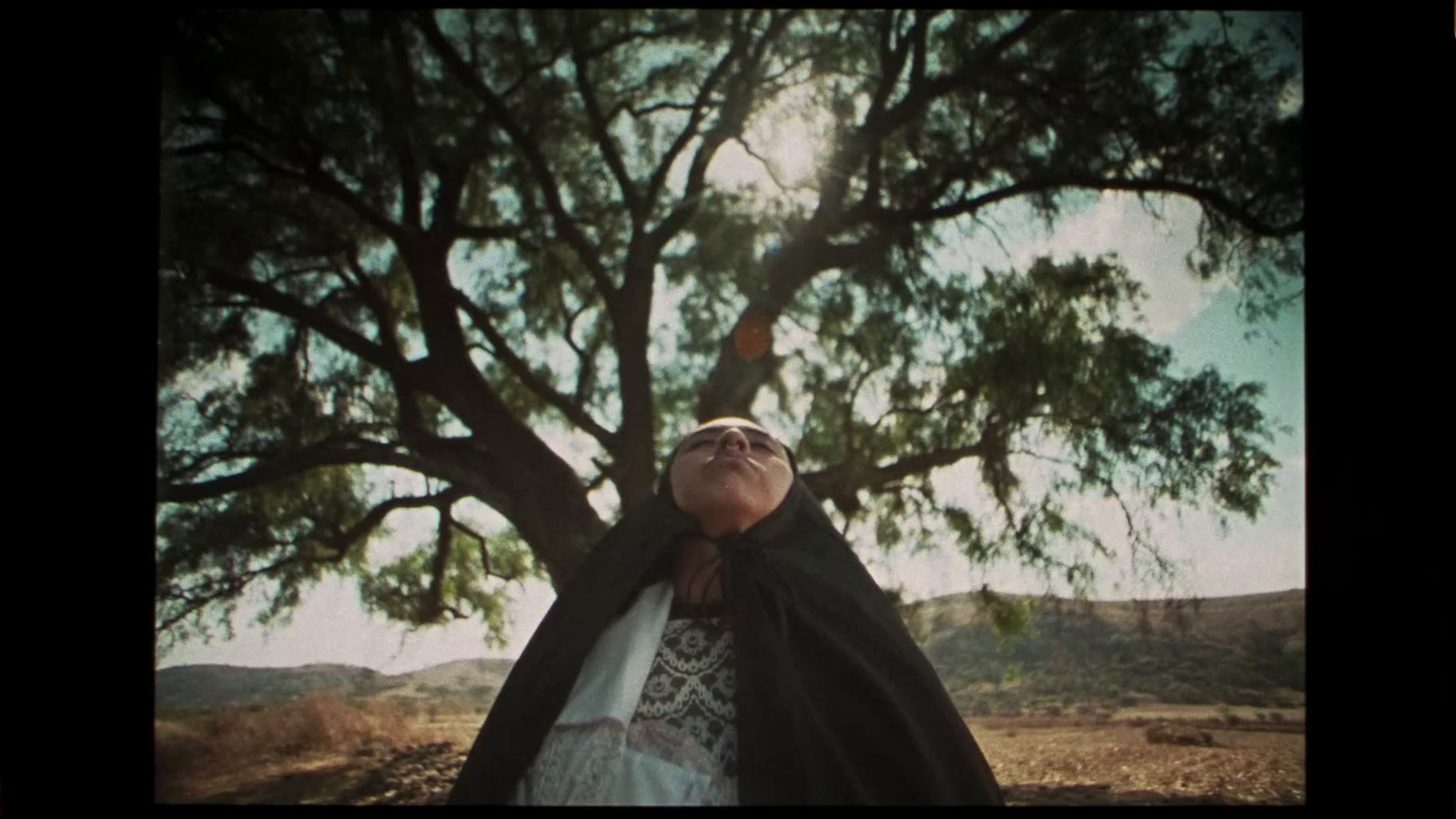 a woman standing under a tree with her eyes closed