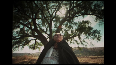 a woman standing under a tree with her eyes closed