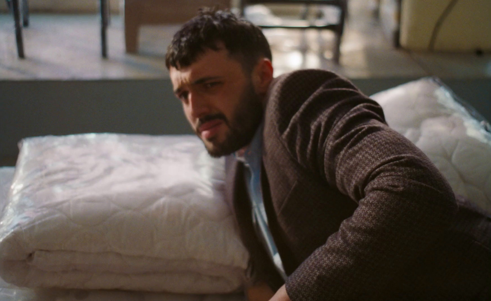 a man sitting on a bed with a pile of pillows