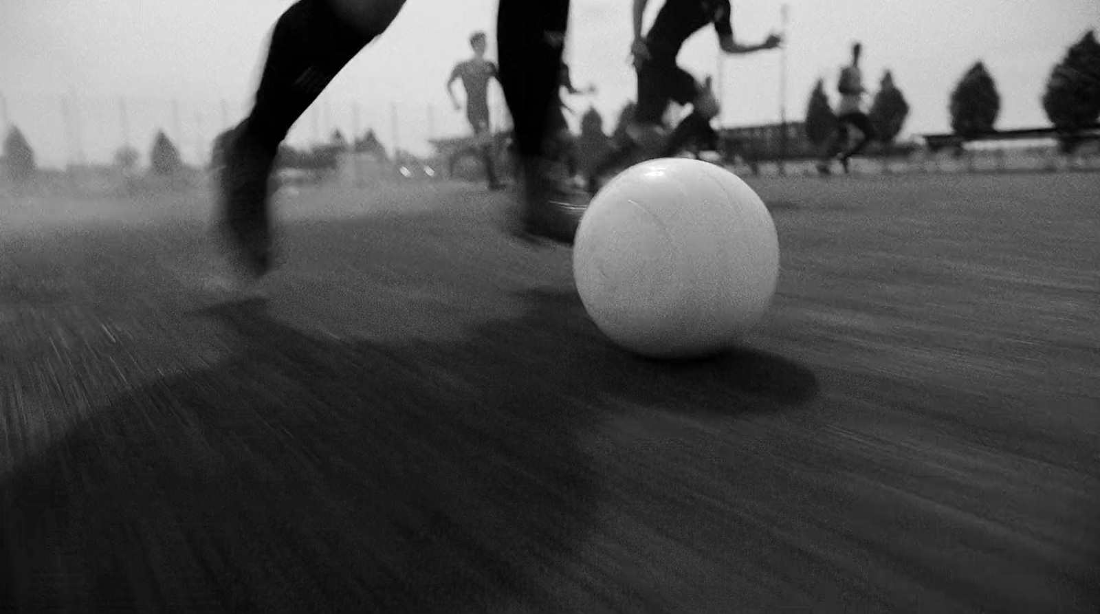 a black and white photo of a person kicking a ball